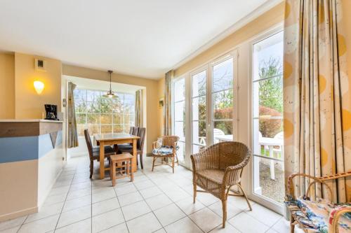 une cuisine avec une table, des chaises et des fenêtres dans l'établissement Les Maisons de Belle Dune - maeva Home - Maison 4 Pièces 8 Personnes Sélection MAE-3688, à Fort-Mahon-Plage