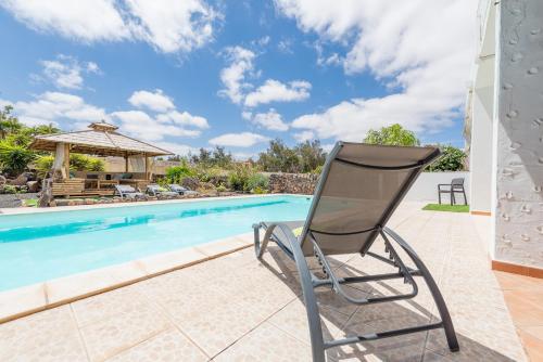 a chair sitting on a patio next to a swimming pool at Casa YUKKA villa with heated pool in Lajares