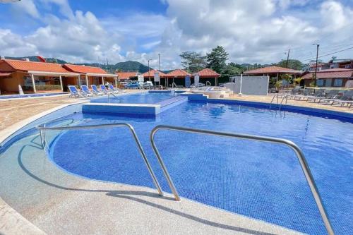 a large swimming pool with blue water and chairs at Villa Paraíso banano 9, near to the beach & Pool in Jacó