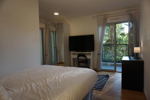 a bedroom with a bed and a television and a balcony at Résidences Grande Jatte, Face Seine, Suites Luxe 52m2 à 97m2, Hôpital Américain à 600m in Neuilly-sur-Seine