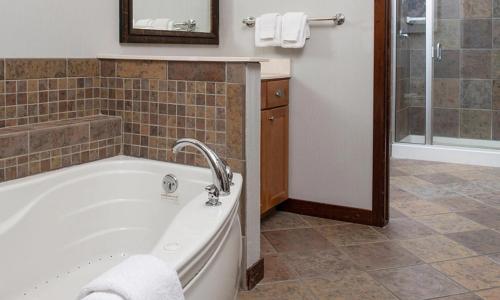 a bathroom with a tub and a shower with towels at Wyndham Glacier Canyon 2 BR in Baraboo