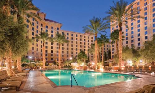 a pool in front of a hotel with palm trees at Wyndham Grand Desert 2 Bedroom in Las Vegas