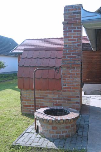 a brick fire pit in front of a house at Füzesi Papa Vendégháza in Harta