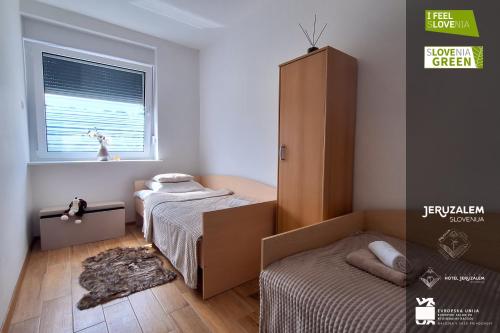 um pequeno quarto com 2 camas e um armário em POD OREHI - Hiša na podeželju - RAZPRŠENI HOTEL Jeruzalem Slovenija em Miklavž pri Ormožu