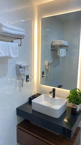 a bathroom with a sink and a large mirror at Bel-air Hotel in Quy Nhon