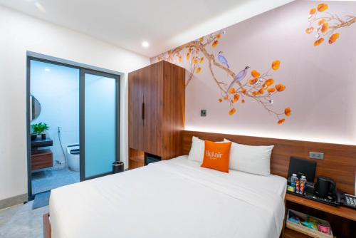 a bedroom with a white bed and a tree on the wall at Bel-air Hotel in Quy Nhon