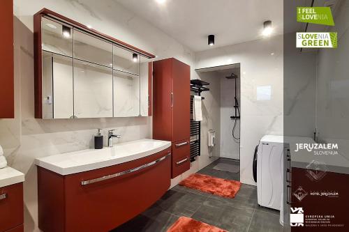 baño con lavabo blanco y armario rojo en POD OREHI - Hiša na podeželju - RAZPRŠENI HOTEL Jeruzalem Slovenija, en Miklavž pri Ormožu