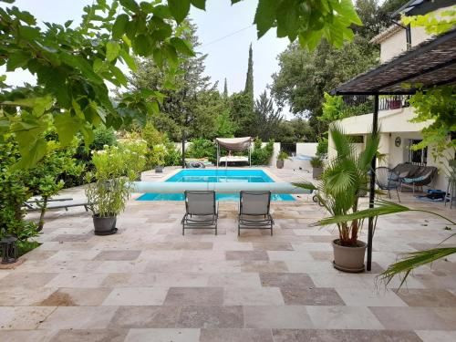 un patio avec des chaises et une piscine dans l'établissement les arbousiers brignoles piscine et spa, à Brignoles