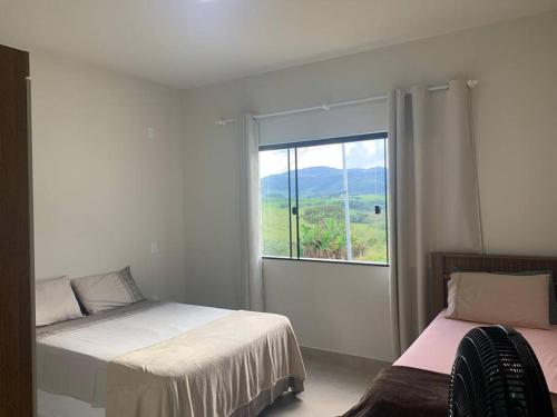 Un dormitorio con dos camas y una gran ventana. en SERRA DA CANASTRA, CASA DO LÉO, en São Roque de Minas