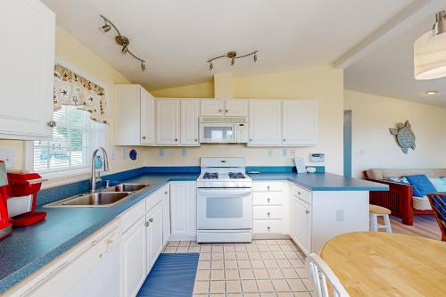 a kitchen with white cabinets and a sink and a table at Bay-View Beauty in Assateague Point in Berlin