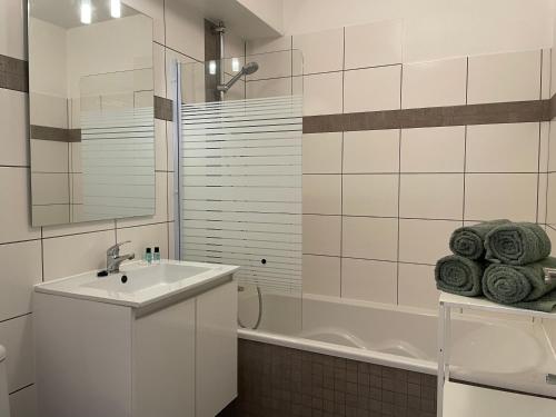 La salle de bains blanche est pourvue d'un lavabo et d'une baignoire. dans l'établissement Studio Ma Préférence, à Horbourg-Wihr