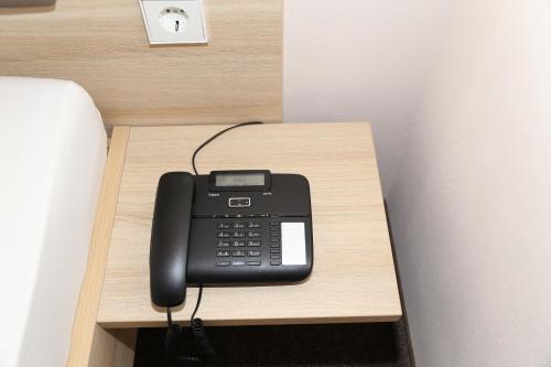 a black phone sitting on a wooden table at Leidringer Gästehaus GmbH in Rosenfeld