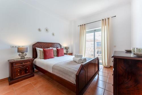 a bedroom with a bed with red pillows and a window at Peaceful 1 BDR Apartment W/ Balcony by LovelyStay in Almancil