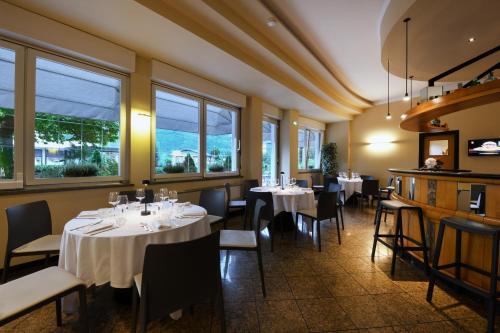 a dining room with tables and chairs and windows at Hotel Internazionale in Domodossola
