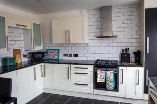 a kitchen with white cabinets and black counter tops at Comfort at Keldy in Tettenhall