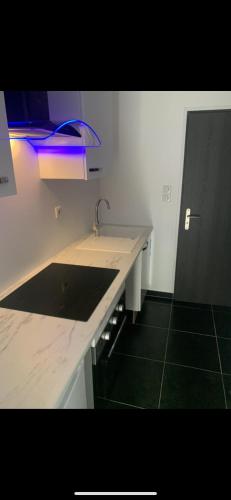 - une cuisine avec un évier et une lumière bleue dans l'établissement Jolie maisonnette Nancy centre, à Nancy