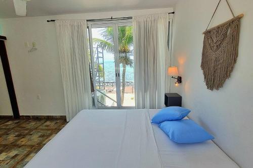a bedroom with a large white bed with blue pillows at On The Beach 2 - Seaside Sunrise Haven- Sea View in Cancún