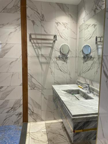 a marble bathroom with a sink and a mirror at درة اجنادين للشقق المخدومة in Tabuk