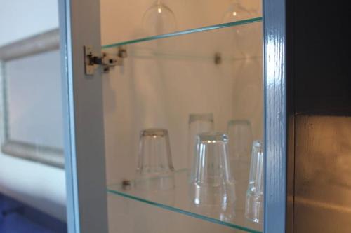 a glass cabinet with some glasses on it at Langley Bungalow in Slough