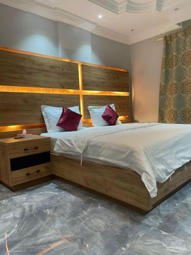 a bedroom with a large bed with purple pillows at درة اجنادين للشقق المخدومة in Tabuk