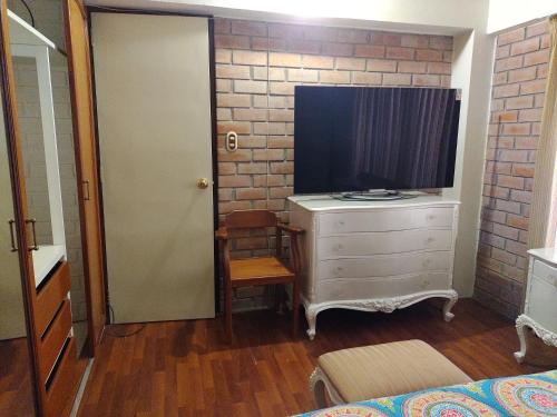 a bedroom with a dresser with a television on it at House garden airport in Zamacola