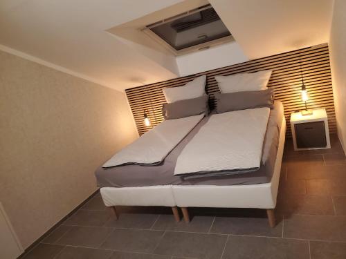 um quarto com uma cama grande com lençóis brancos e almofadas em Ambiente Feriendomizil em Weilerswist