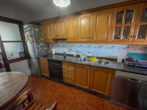 a kitchen with wooden cabinets and a sink and a table at Lourdes 1 casa compartida solo con la anfitriona in Breña Baja