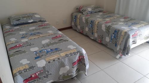 two beds in a room with trains on the covers at Férias em Família Apartamento Temporada in Cabo Frio