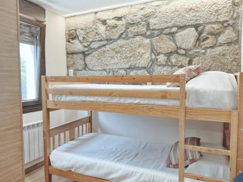 a room with two bunk beds in front of a stone wall at Apartamento Albar in Poio