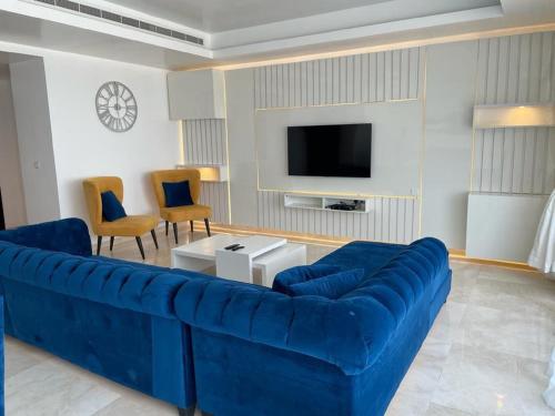 a living room with a blue couch and a tv at The Vistana Eko Pearl Towers Apartment in Lagos