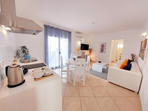 a white kitchen and living room with a couch and a table at Branco Suites - Rooms & Holiday Apartments in Santa Maria