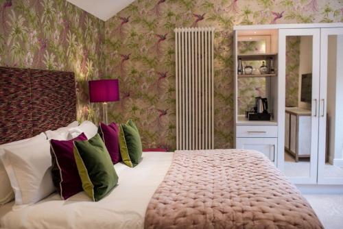 a bedroom with a large bed with green and purple pillows at Dewars Restaurant and Rooms in Malton