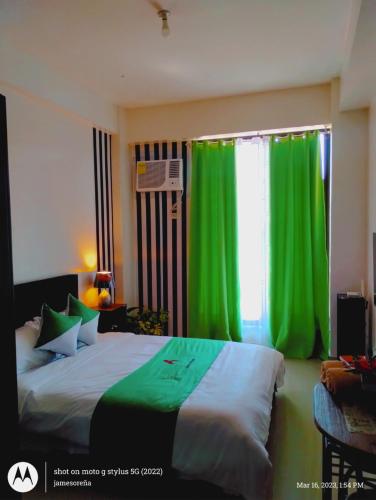 um quarto com uma cama com cortinas verdes e uma janela em Jenny N Rose Travellers Inn em Manila