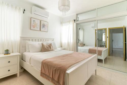 a white bedroom with a large bed and a mirror at Relax Apartment to enjoy! in Santiago de los Caballeros