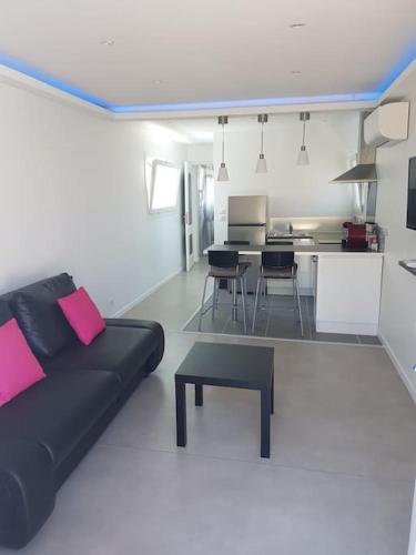 un salon avec un canapé noir et une cuisine dans l'établissement Coquet et confortable Appartement T2, à Rognac