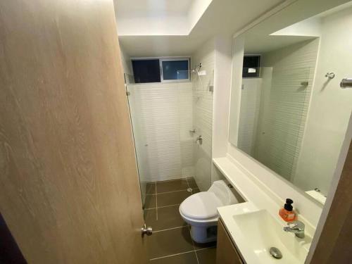 een badkamer met een toilet, een wastafel en een spiegel bij Hermoso apartamento in Ricaurte