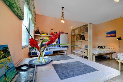 a room with a table with a vase with red flowers at Cabarete Boutique Kite Hotel Garden Loft in Cabarete