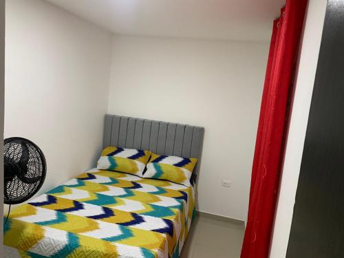 a small bedroom with a bed with a colorful comforter at APARTAMENTO EN VALLEDUPAR in Valledupar