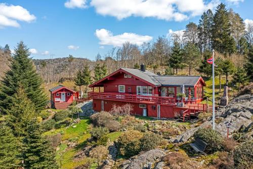 ein rotes Haus an der Seite eines Berges in der Unterkunft Gemütliches helles Ferienhaus am See mit Panoramaseeblick + Hütte und nahe Meer in Lyngdal