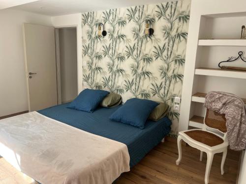 ein Schlafzimmer mit einem Bett mit blauen Kissen und einer Tapete in der Unterkunft L'intemporel 
