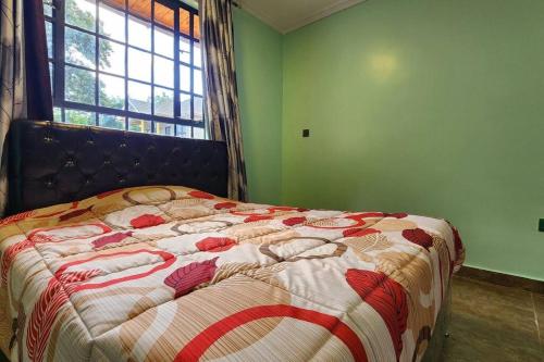 um quarto com uma cama com uma colcha e uma janela em Ace House em Nyeri