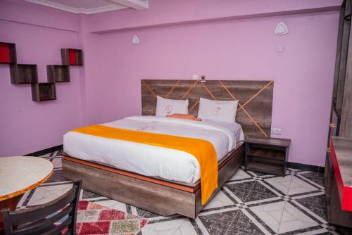 ein Schlafzimmer mit einem großen Bett mit einer orangefarbenen Decke in der Unterkunft Hotel Good Putt in Nakuru