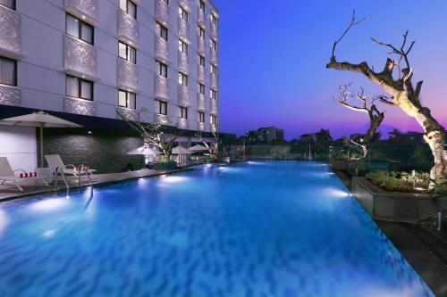 a swimming pool in front of a hotel at night at Hotel Neo Malioboro by ASTON in Yogyakarta