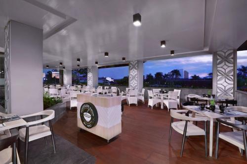 a restaurant with white tables and white chairs at Hotel Neo Malioboro by ASTON in Yogyakarta