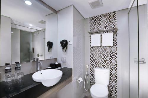 a white bathroom with a sink and a toilet at Hotel Neo Malioboro by ASTON in Yogyakarta