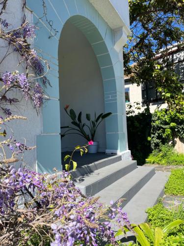 a blue building with stairs and purple flowers at La Posada Coliving in Viña del Mar