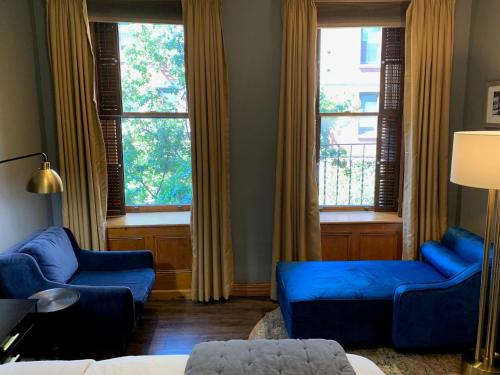 a living room with two blue couches and two windows at The Historic Blue Moon Hotel - NYC in New York