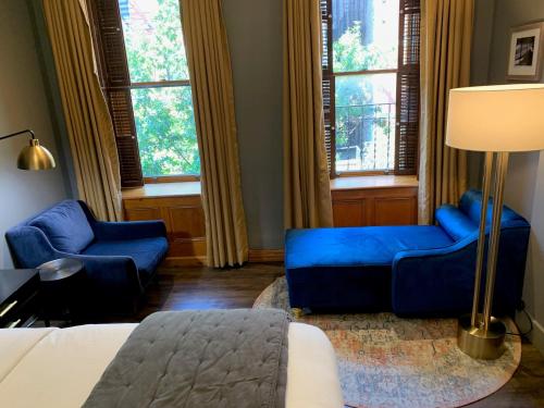 a living room with blue furniture and windows at The Historic Blue Moon Hotel - NYC in New York