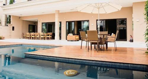 uma mesa de jantar com um guarda-sol ao lado de uma piscina em Class Hotel Alfenas em Alfenas
