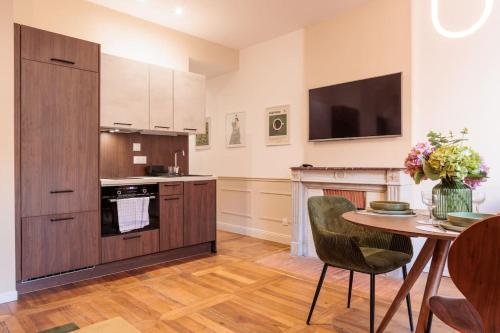 a kitchen with a table and a tv on the wall at Le VB du 21 in Bourg-en-Bresse